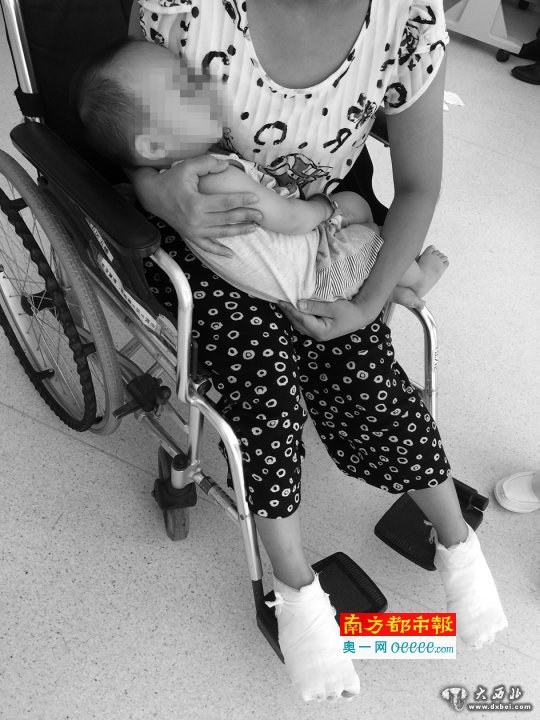 双脚被烫伤的母亲坐在轮椅上抱着儿子。